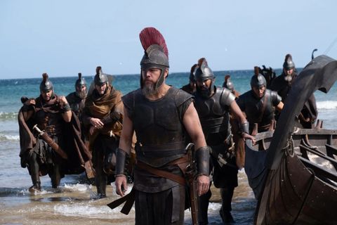 Matt Damon en Ulysse, casque à haut cimier de crin rouge et cuirasse de cuir, remonte la plage à la tête de ses soldats qui tirent leur navire hors des vagues.